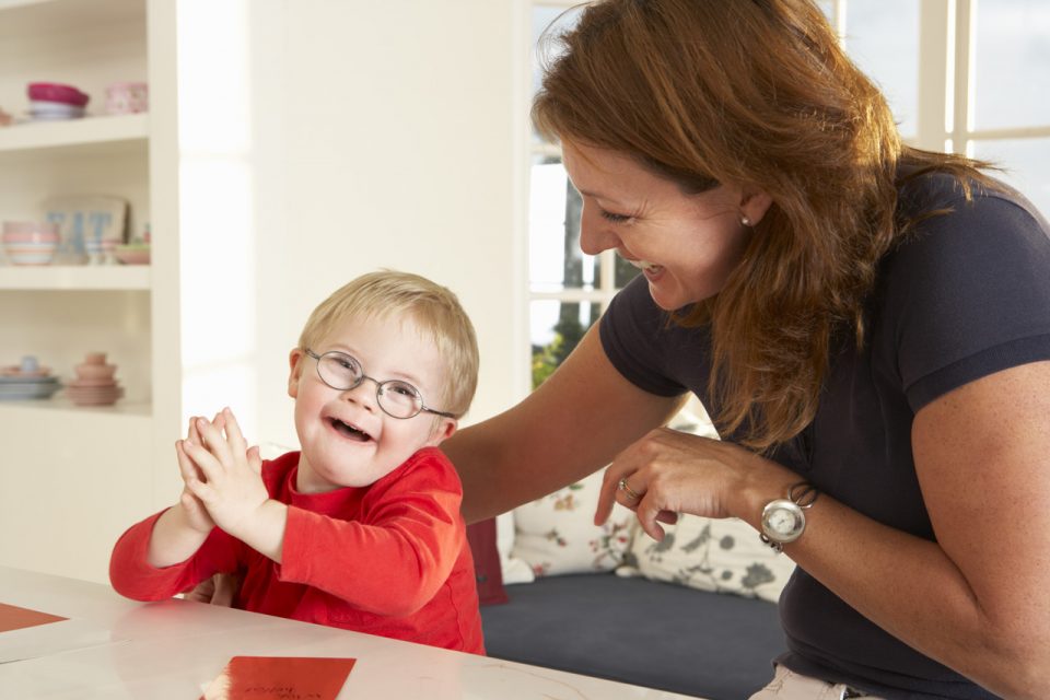 Mom and child wearing red shirt sitting at kitchen bar smiling playfully